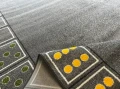Dywan Z WZOREM DOMINO - zdjęcie, ramowy układ wzoru ułożony z kostek domino, z jednolitym szarym środkiem - zbliżenie runa i spodu dywanu